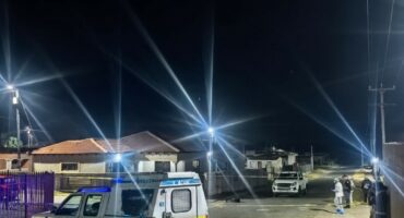 mage of a police van at night with forensic officers combing the area.