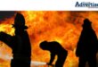 Three siluettes of fire fighters fighting a fire.