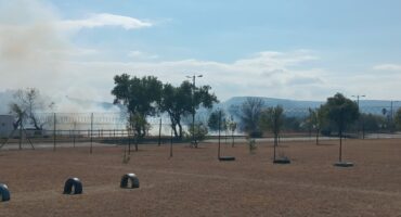Image of smoke rising from a dry field in the foreground.