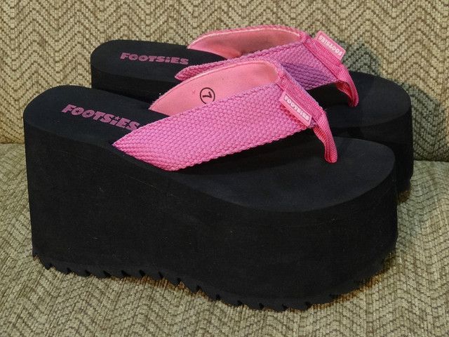A pair of pink and black platform flip flops.