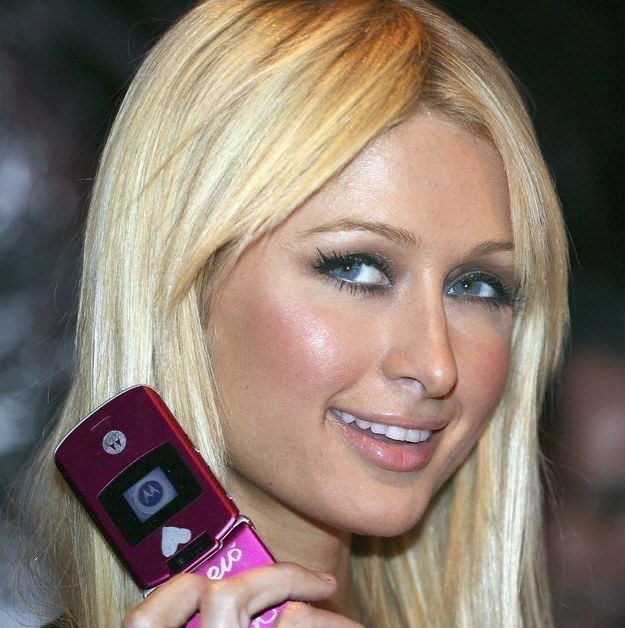 A celebrity is photographed with her pink flip phone in her hand.
