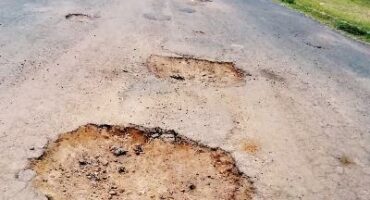 Image of two potholes in Dundee with a vehicle in the background.