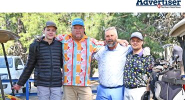 A group of golfers posed for a photo in front of a golf cart.