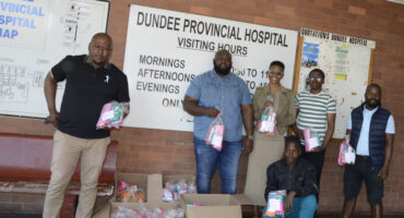 Image of men giving out Women's Day packages at Dundee Hospital.