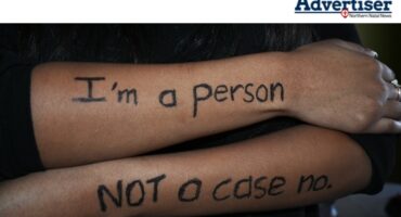 A photo of a young girl''s folder arms with "I'm a person not a case no" written on them.