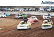 Several oval track cars are photographed on a dirt track.