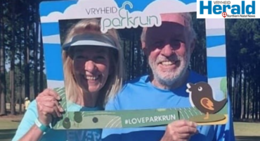 Image of male and female holding a Vryheid parkrun photo 'booth'.