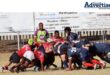 A Photo of two rugby teams in a scrum on a rugby field, in front of a referee.