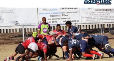 A Photo of two rugby teams in a scrum on a rugby field, in front of a referee.