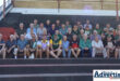 A large group of elderly, former Newcastle rugby players sitting on a pavillion.