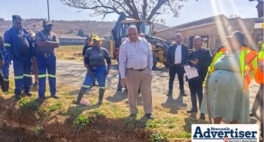 Several municipal management members and workers are photographed stnding by a water leak in Newcastle.