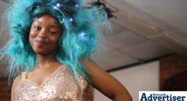 A young model is pictured with blue hair on the runway.