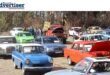 A photo of a large display of vintage cars, with spectators admiring the vehicles.
