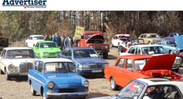 A photo of a large display of vintage cars, with spectators admiring the vehicles.