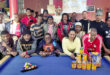 Image of pool players around a pool table with tins of pet food donated to the Dundee SPCA.