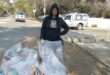 Image of a woman with litter she picked up and put in refuse bags.