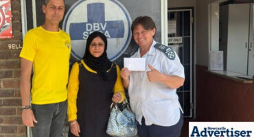 Three people stand in front of the Newcastle SPCA offices holding a cash donation.