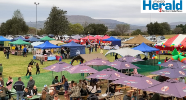 Image of tents, gazebos and people on a rugby field.