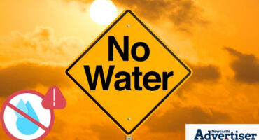 A yellow 'No Water' sign in front of a yellow sunny and cloudy background with the Newcastle Advertiser logo in the bottom corner.