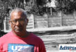 Ward Committee Member, Mr V Singh (in colour) poses in front of a damaged road.