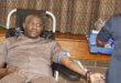 Image of a man giving blood with a nurse standing next to him.