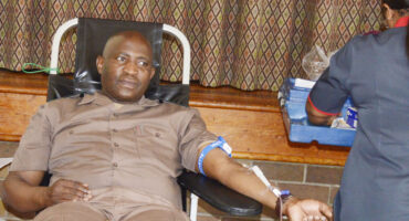 Image of a man giving blood with a nurse standing next to him.