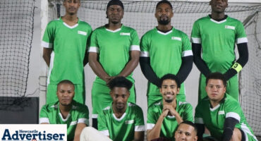 A team photo of a soccer team taken in Newcastle in their green uniform.