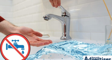 A tap without water in the backgrounjd with hands waiting for the water. A water strip and the Newcastlle Advertsier logo is at the bottom nd accros the picture. A white, red and blue no water warning is also seen.