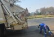Image of a municipal dump truck with a worker picking up litter.