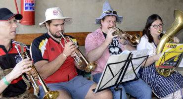 Image of men dressed in traditional German garb playing brass instruments.