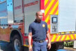 Image of a uniformed fireman in front of a fire engine.