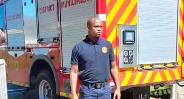 Image of a uniformed fireman in front of a fire engine.