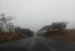 Image of a wet road, grey sky and a bridge/