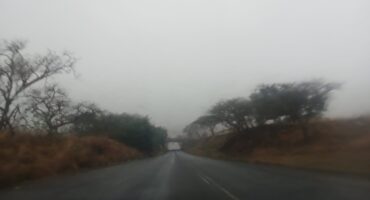 Image of a wet road, grey sky and a bridge/
