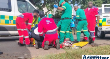 A group of paramedics at a scene treating an injured patient.