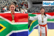 Image of mother and daughter holding the South African flag in their karate kits.