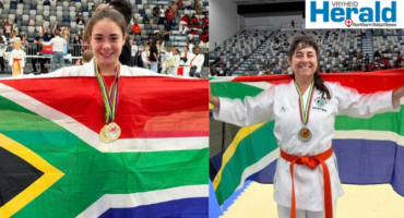 Image of mother and daughter holding the South African flag in their karate kits.