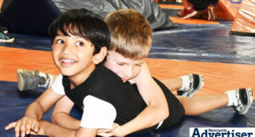 Two young children are photographed on the wrestling mat.
