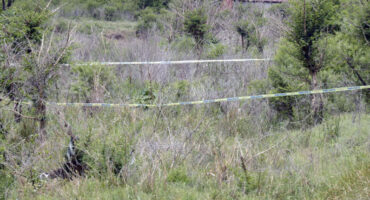 A cordoned off crime scene area in a field.