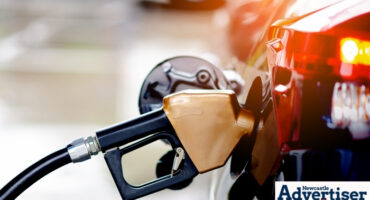 A photo of a petrol station, with a petrol guzzle inside a vehicle tank.