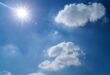 Image of the sun in the sky with a few clouds.