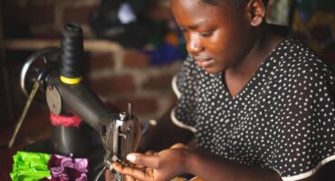 Image of a woman working on a sewing machine.