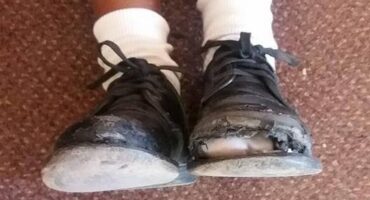 Image of two battered school shoes worn by a child.