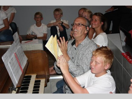 Prof Awie van Wyk , omring deur lede van die kinderkoor wat deelgeneem het aan die Musiekfees Woensdagaand, juig deelnaemers van die fees toe.