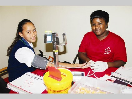 Mitchell House College learner, Kariemam Tayob, makes sure her blood pressure is optimal for blood donation, assisted by Thatcher Malesa.