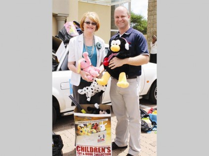 RE/MAX Northland Realty personeel oorhandig speelgoed en boeke aan Maryna Kruger en Hetta Hamman van Hoop vir Kinders.