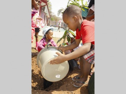 Vhuyeni Matumba (in front) and Ditebogo Maenletja from Share Joy Pre-school help to plant trees at the school.