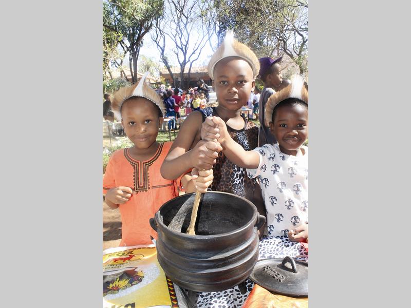 Pap is a truly African dish. Here Bilal Monumangene, Buhla Ngema and Wandile Mphephu stir the pot, dressed up in African cultural attire for the Montessori Centre's Heritage Month celebrations.