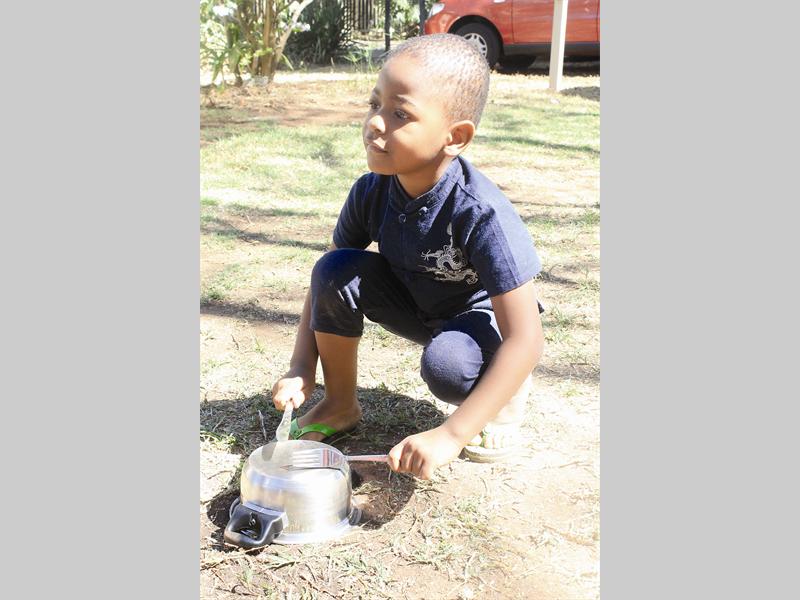 Mukundi Mathlako uses a fork, a knife and a pot to play drums and makes music for his friends at the Montessori Centre.