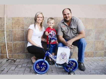 Freek van den Bergh (3) cannot wait to get onto his new bicycle. With him are his mother Laetitia and Hannes Willemse (Nguni Grill, owner)